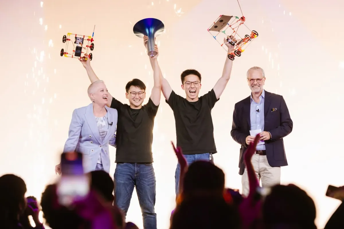 The Stick ’Em founders on the Hult Prize 2025 stage, holding the trophy and two chopstick builds above their heads