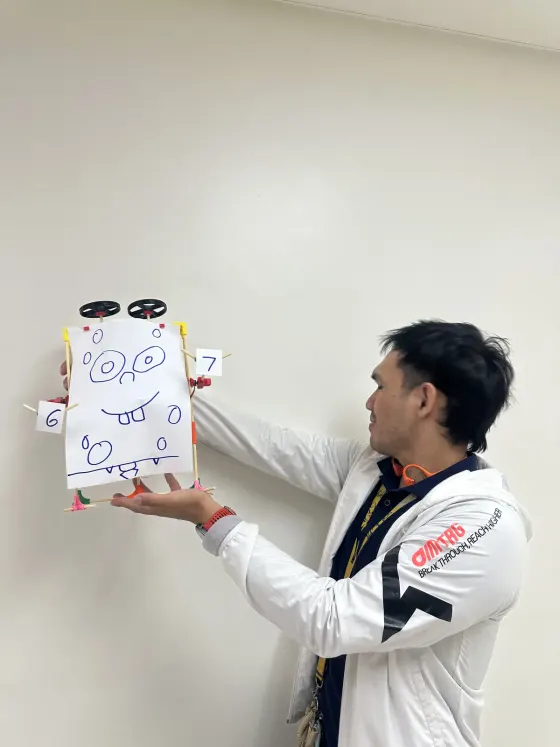 A teacher holding up a finished build to the room